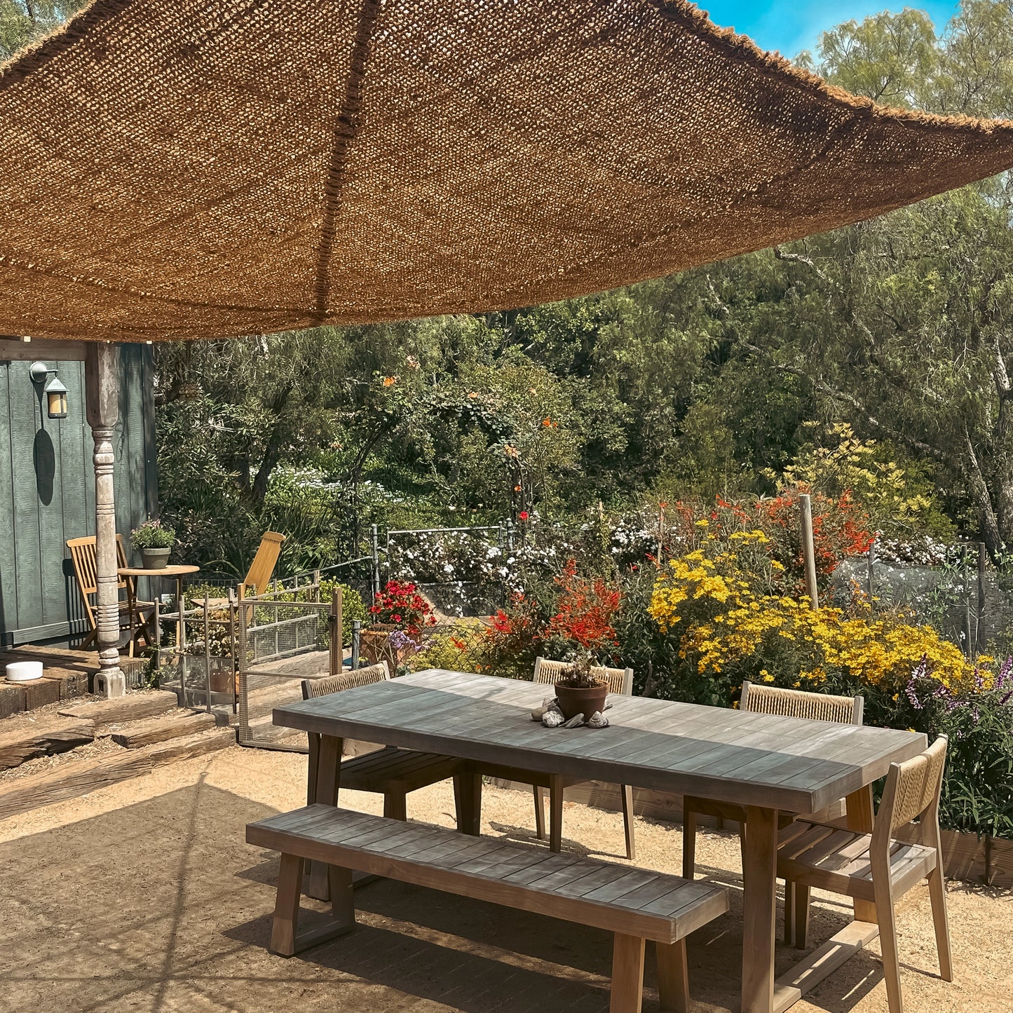 10ft x 13ft rectangle shade sail providing patio shade over an outdoor dining area surrounded by garden flowers.
