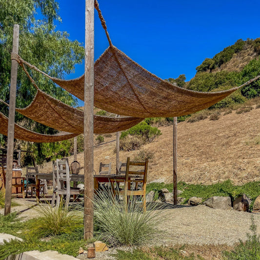 Multiple 7ft x 10ft rectangle shade sails installed above an outdoor dining table in a sunny backyard setting.