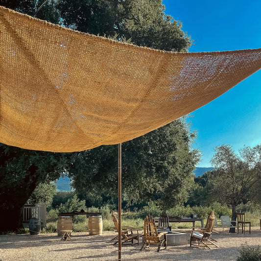 10ft x 10ft square shade sail made from coconut fiber, installed at a vineyard next to an outdoor fire pit and lounge area.