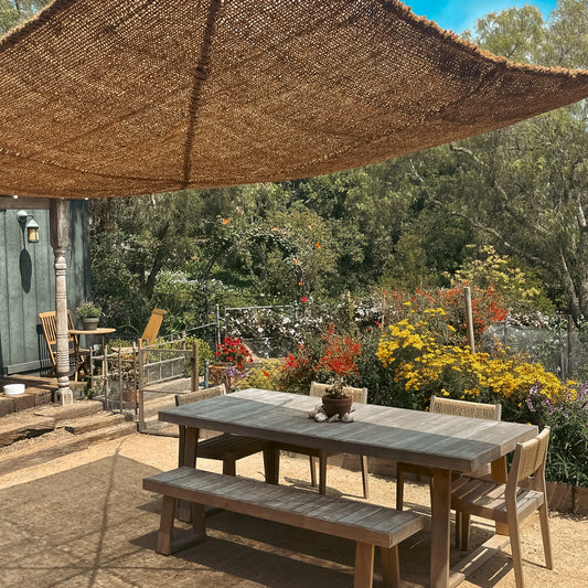 10ft x 13ft rectangle shade sail providing patio shade over an outdoor dining area surrounded by garden flowers.